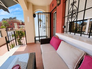 A balcony with a sofa, a table, and a view of the cityscape. - Altos de la Bahía Spacious Townhouse With Private Garden & Pool (Torrevieja)
