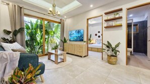 Una sala de estar moderna con televisor, sofá, mesa de centro y comedor.