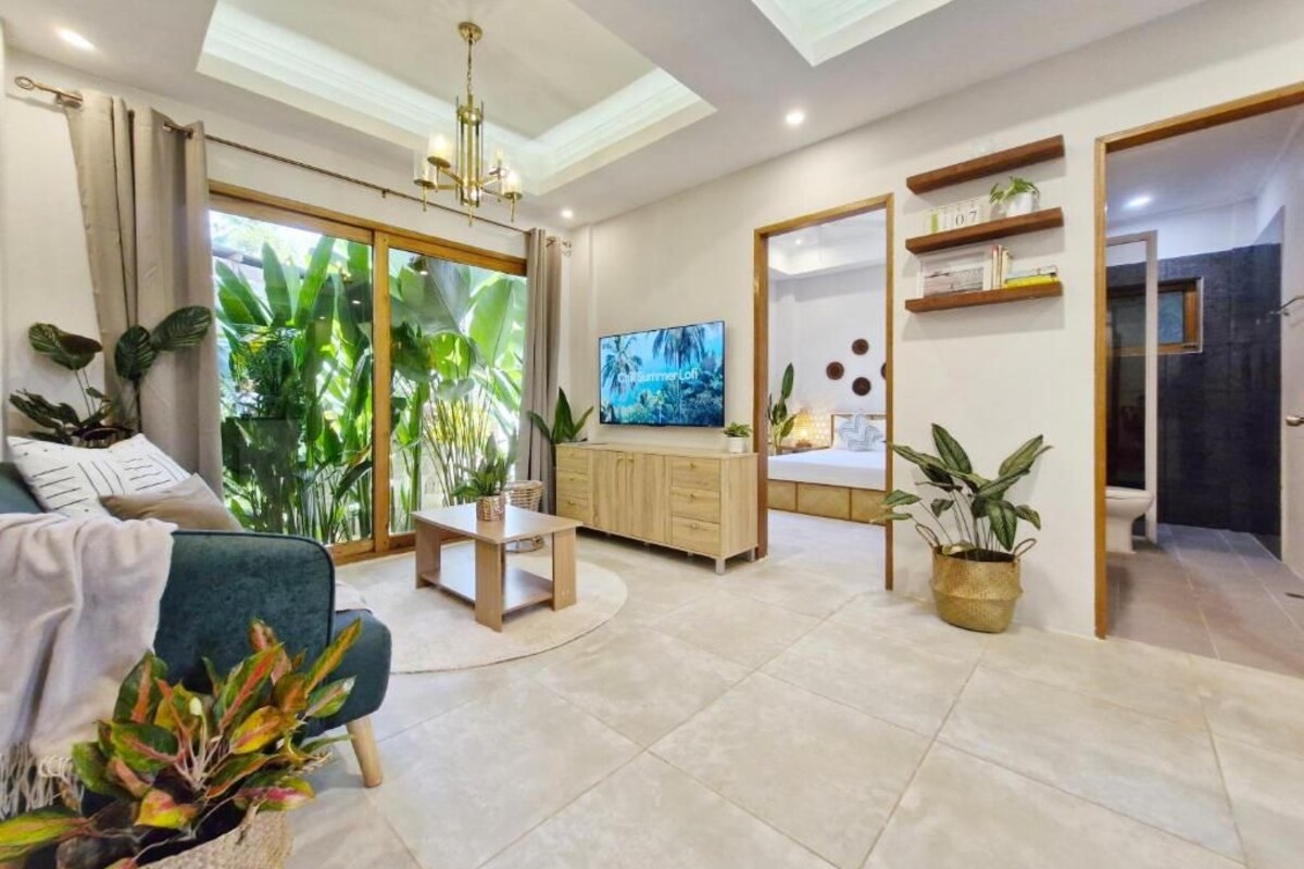 A modern living room with a television, a sofa, a coffee table, and a dining area.