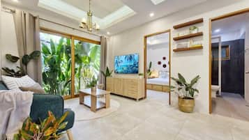 A modern living room with a television, a sofa, a coffee table, and a dining area.
