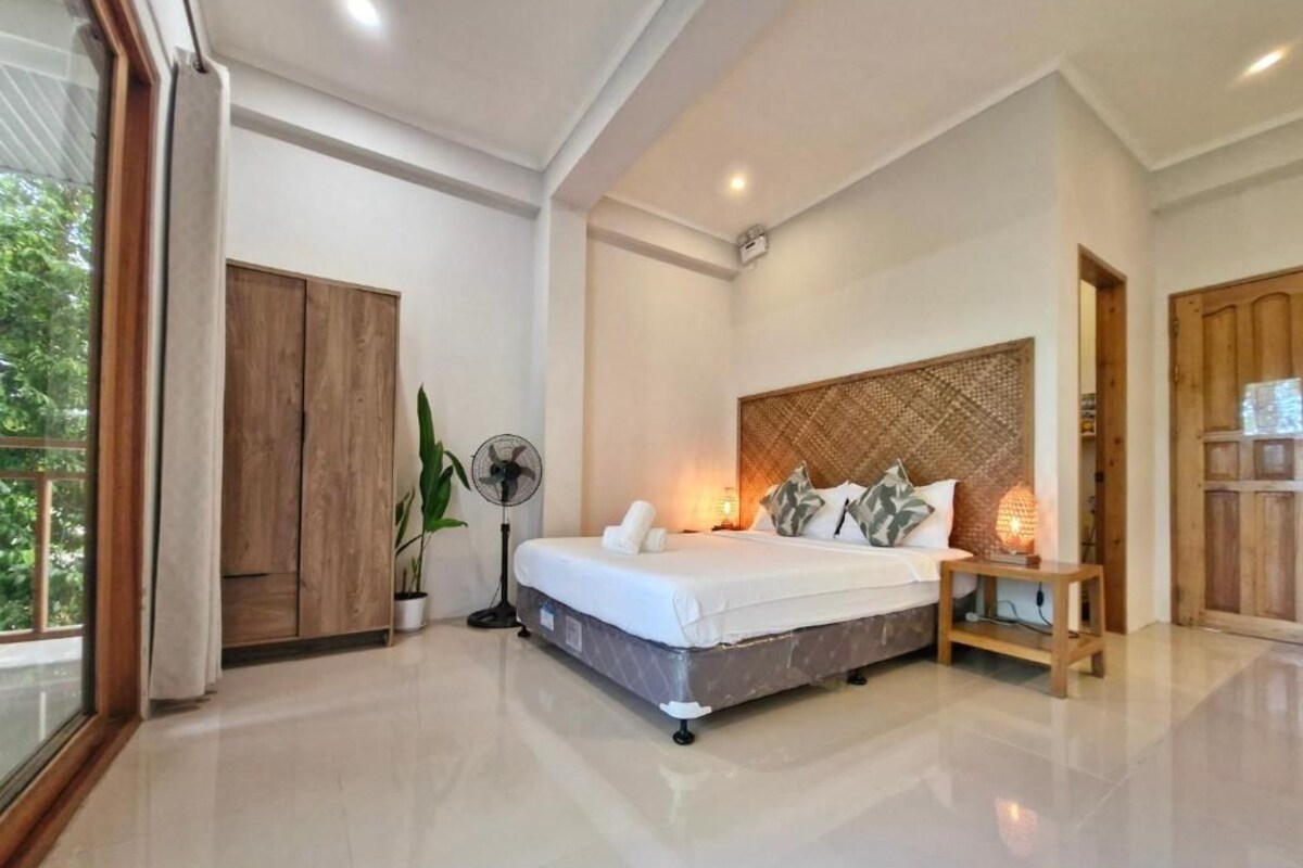 A bedroom with a bed, bedside table, and a fan.