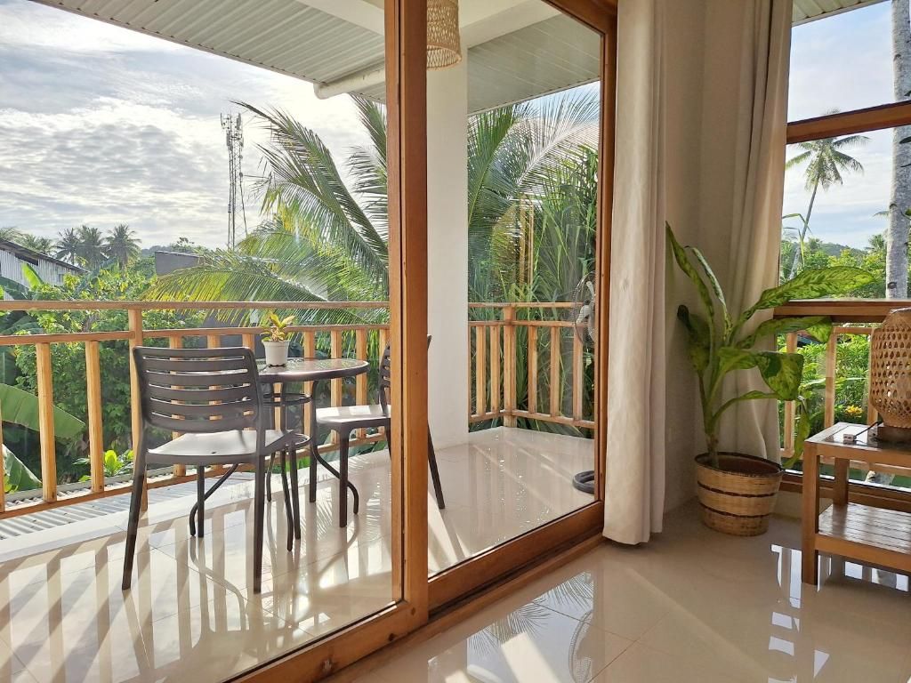 A balcony with a glass door, a table with chairs, and a potted plant.