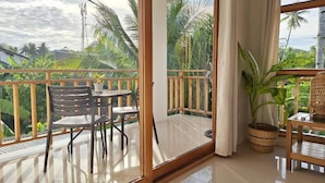 Un balcón con puerta de cristal, una mesa con sillas y una planta en maceta.