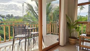 A balcony with a glass door, a table with chairs, and a potted plant.