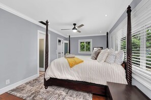 Un dormitorio con cama con dosel, ventilador de techo y ventana con persianas.