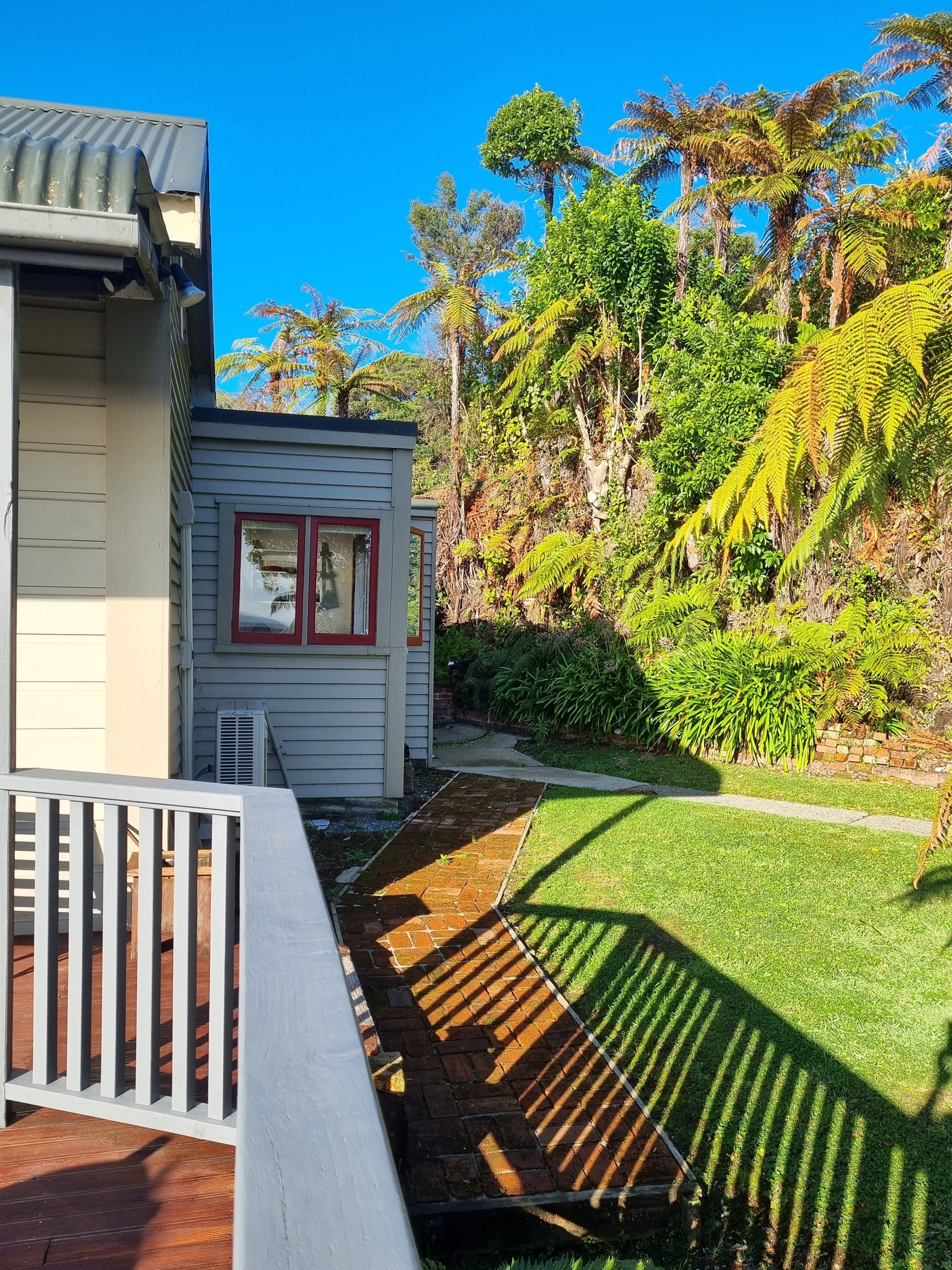 A residential property with a small shed, a well-maintained lawn, and a variety of trees and shrubs.
