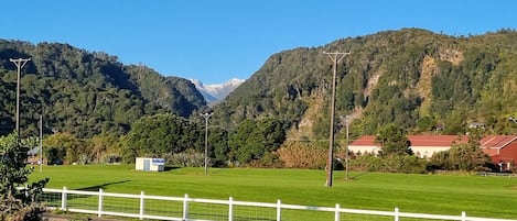 Paisaje rural con una carretera, cerca blanca y casas con tejados rojos.