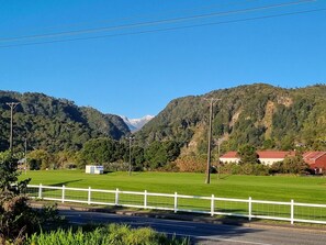 Paisatge rural amb carretera, valla blanca i cases amb teulades vermelles.