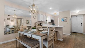 A dining area with a wooden table and chairs, a chandelier, and a kitchen in the background. - Birdie's Nest and 2bdr Condo (Branson)