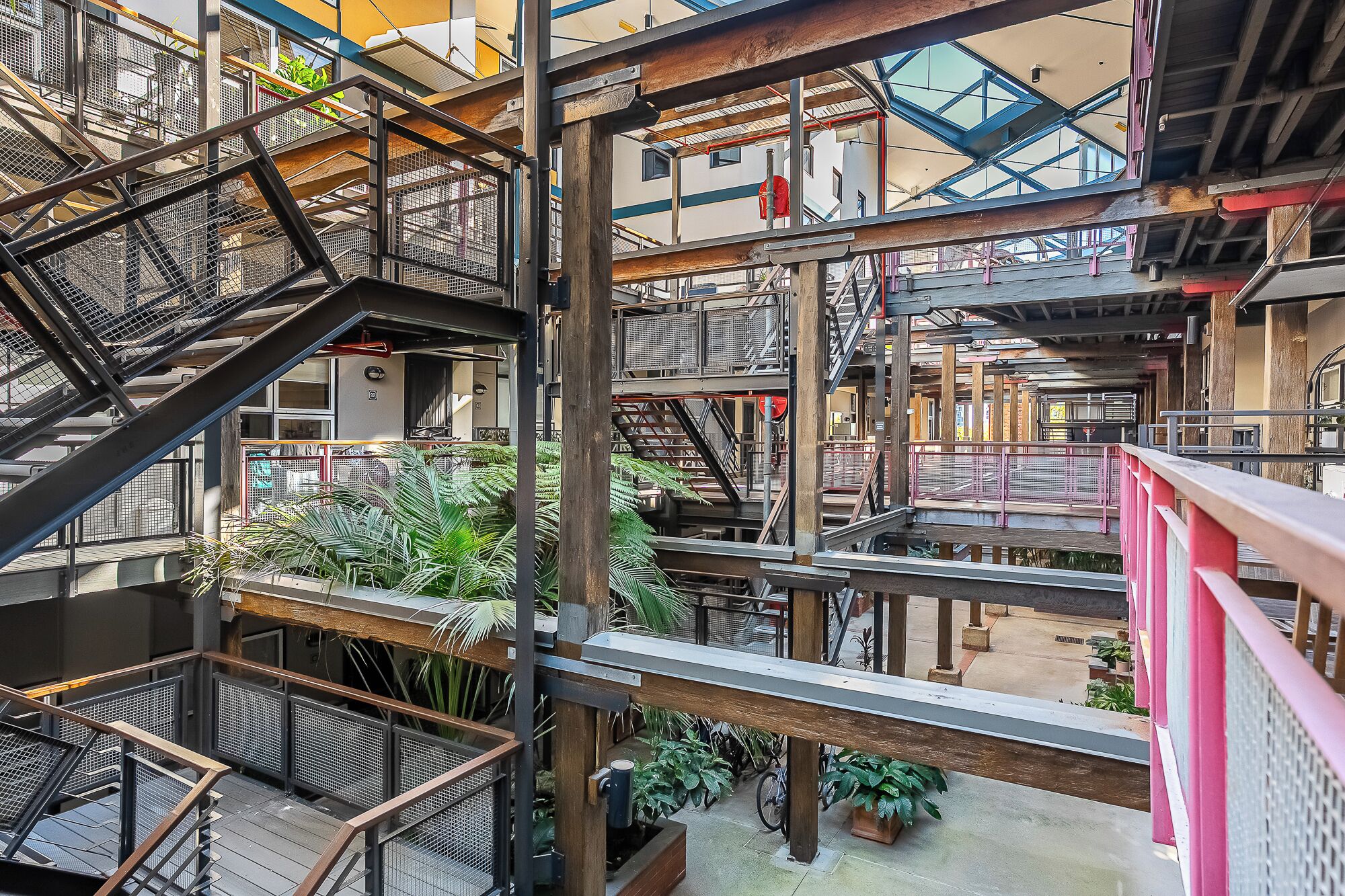 Ein mehrgeschossiges Atrium mit Metalltreppen und Geländern, umgeben von Topfpflanzen.