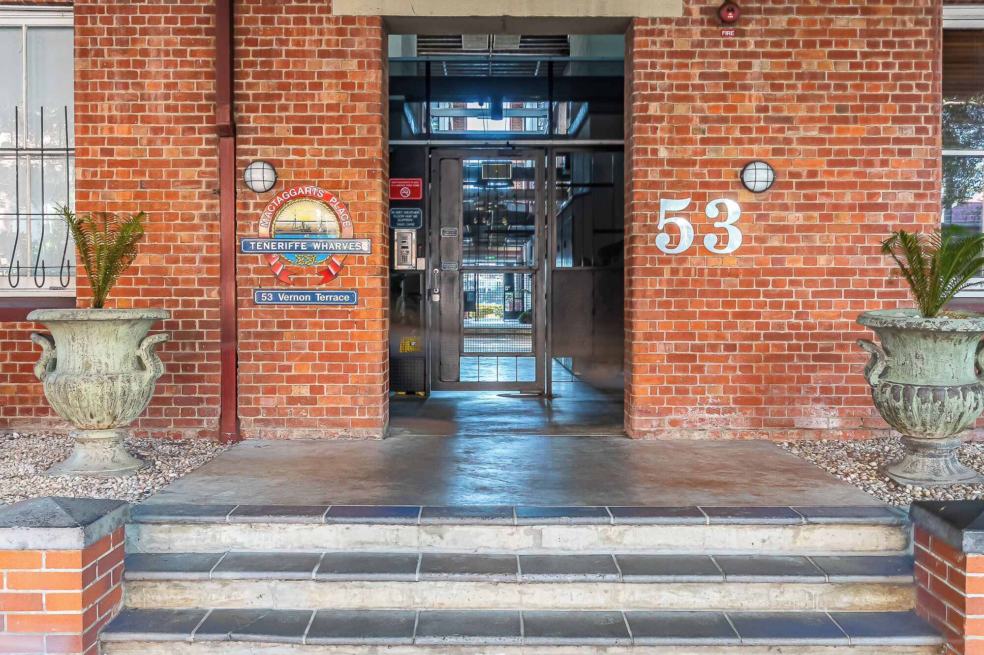 A brick building entrance with a sign indicating 'Actaggarts Place' and the number '53' on the wall.