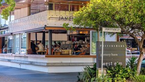 A restaurant with outdoor seating, a visible kitchen, and a sign indicating 'Pottery Barn Kids' and 'West Elm'. - Mactaggarts Place Apartments (Teneriffe)