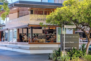 A restaurant with outdoor seating, a visible kitchen, and a sign indicating 'Pottery Barn Kids' and 'West Elm'. - Mactaggarts Place Apartments (Teneriffe)