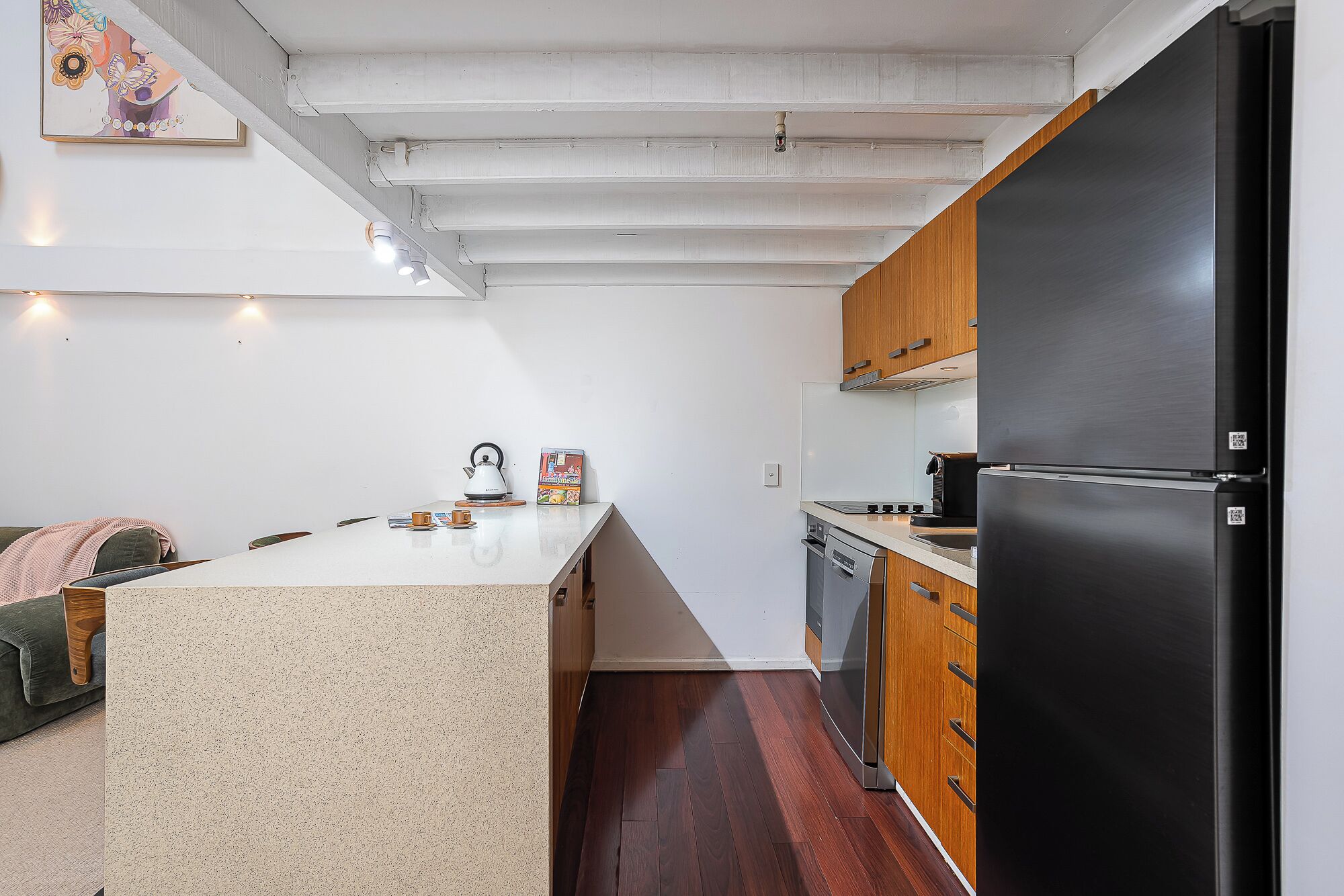 A compact kitchen with a central island, wooden cabinets, and a black refrigerator.