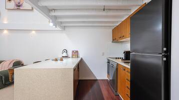 A compact kitchen with a central island, wooden cabinets, and a black refrigerator.