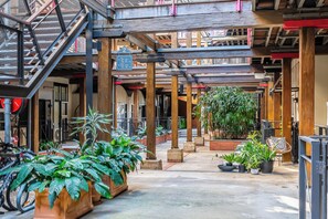 An indoor courtyard with wooden beams, potted plants, and a staircase. - Mactaggarts Place Apartments (Teneriffe)
