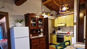 Une cuisine de taille réduite avec un réfrigérateur blanc, des placards en bois, un évier jaune et une cuisinière.