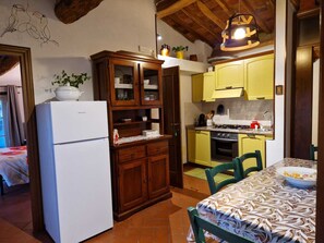 A compact kitchen with a white refrigerator, wooden cabinets, a yellow sink, and a stove. - In Celli, Between the Woods and the Sky - Apartment in an Old Farmhouse Surrounded by Greenery (San Martino in Freddana - Monsagrati)