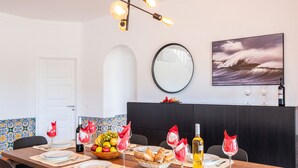 A dining area with a table set for four, a fruit basket, wine glasses, and a bottle of wine.