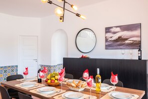 A dining area with a table set for four, a fruit basket, wine glasses, and a bottle of wine.