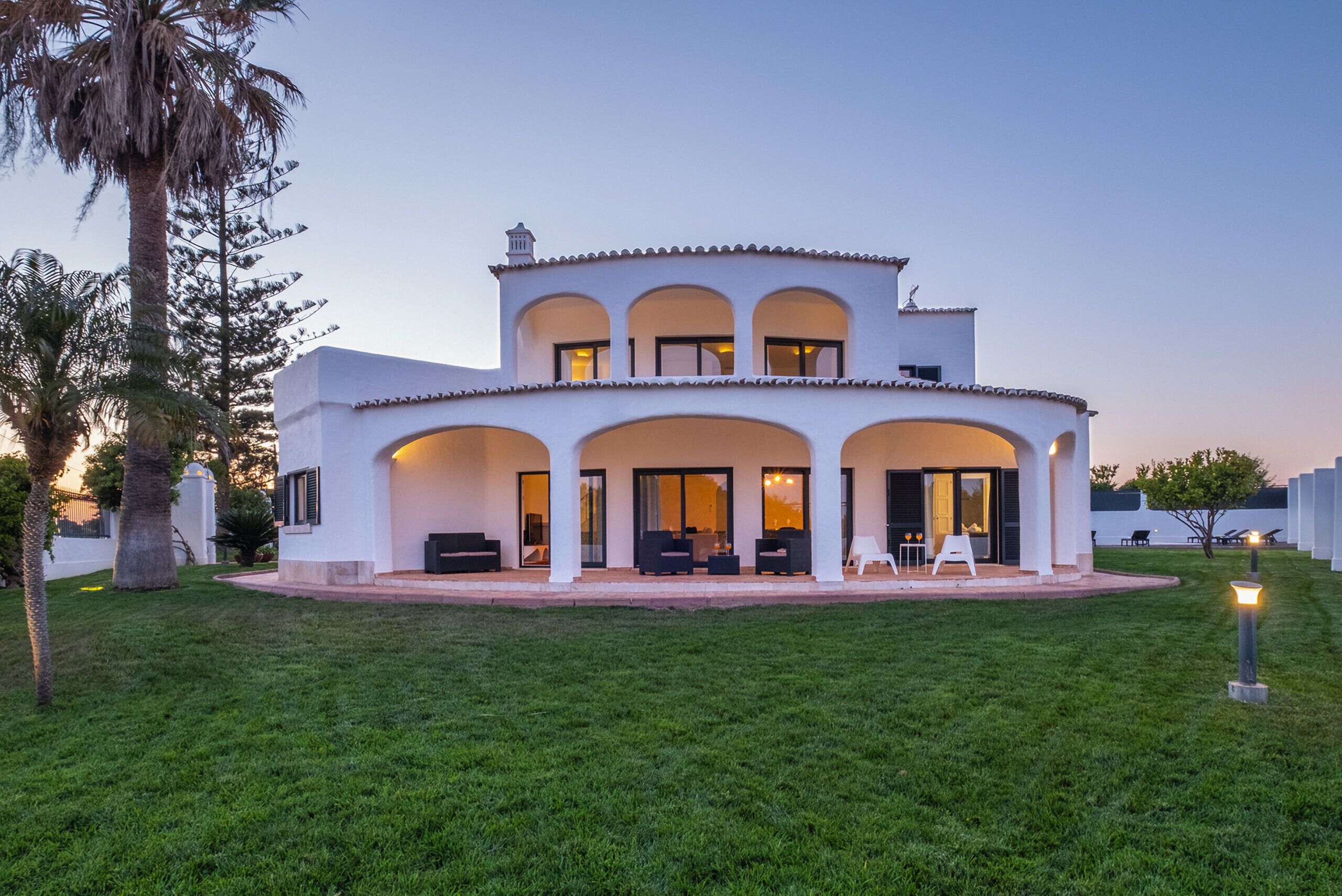 A two-story house with a covered patio, outdoor seating, and a well-maintained lawn.