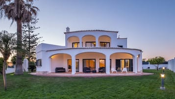 A two-story house with a covered patio, outdoor seating, and a well-maintained lawn.