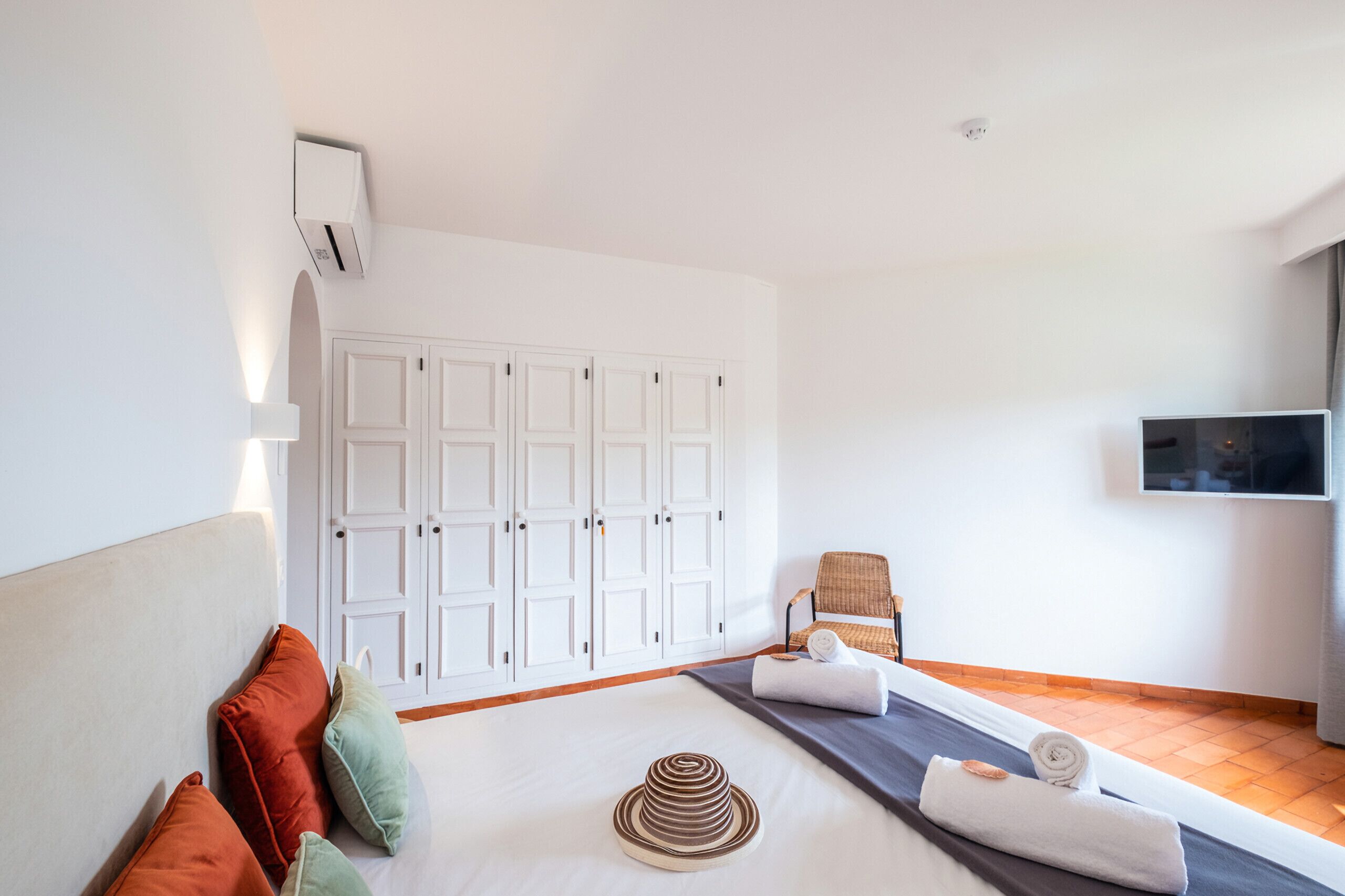 A hotel room with a bed, a chair, a TV, and a wardrobe.