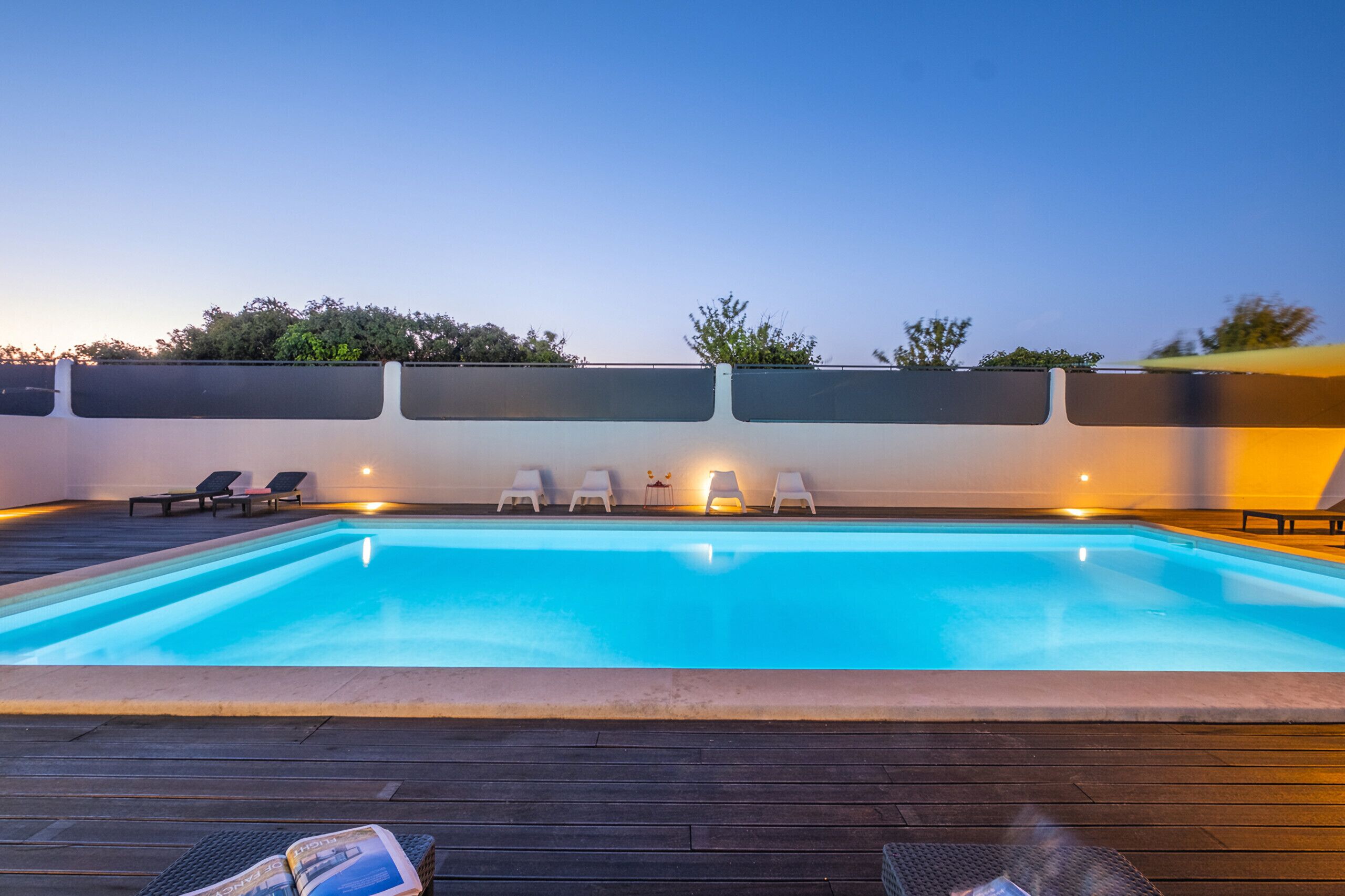 A swimming pool with lounge chairs and a wooden deck.