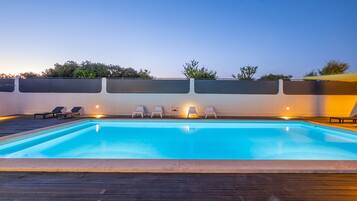 A swimming pool with lounge chairs and a wooden deck.