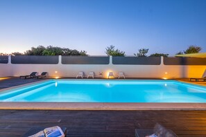 Une piscine avec des chaises longues et une terrasse en bois.