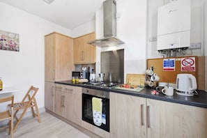 A modern kitchen with wooden cabinets, stainless steel appliances, and a coffee machine.