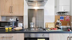 Una cocina moderna con electrodomésticos de acero inoxidable, armarios de madera y encimera negra.