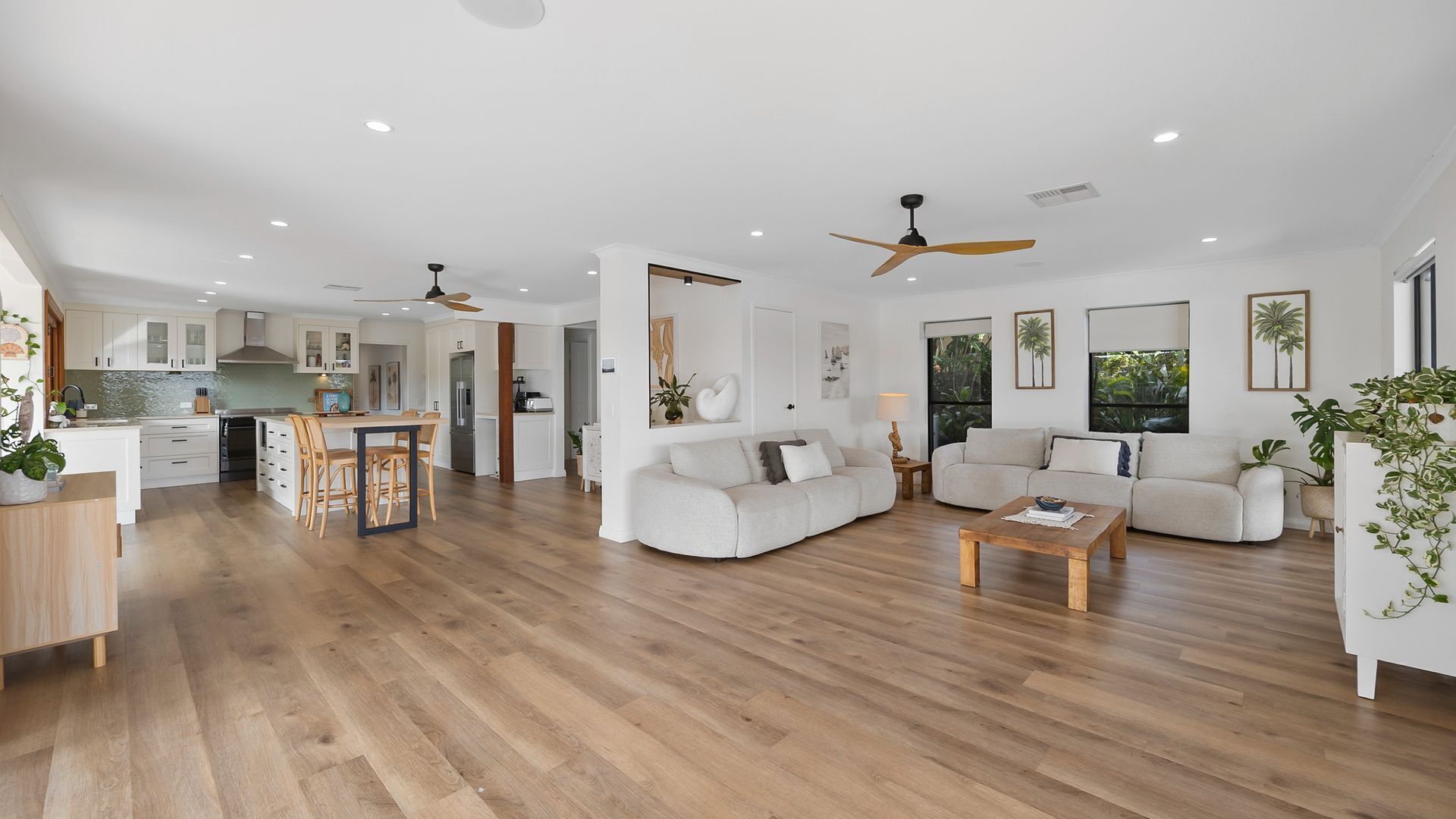 A spacious living area with a dining table, sofas, and a kitchen in the background.