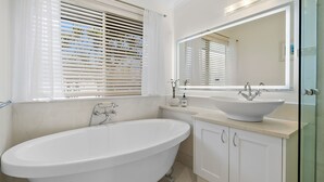A modern bathroom with a freestanding bathtub, a large mirror, and a sink with a vessel basin. - Waterfront Retreat in the heart of Mooloolaba (mooloolaba)