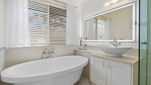 A modern bathroom with a freestanding bathtub, a large mirror, and a sink with a vessel basin. - Waterfront Retreat in the heart of Mooloolaba (mooloolaba)