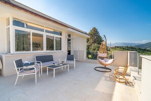 A terrace with outdoor furniture, a hanging chair, and a view of the landscape. - Casa Musica: Villa Suite with Panoramic Pool (Giardini Naxos)