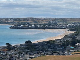 Un pueblo costero con playa, casas y un paisaje montañoso al fondo.