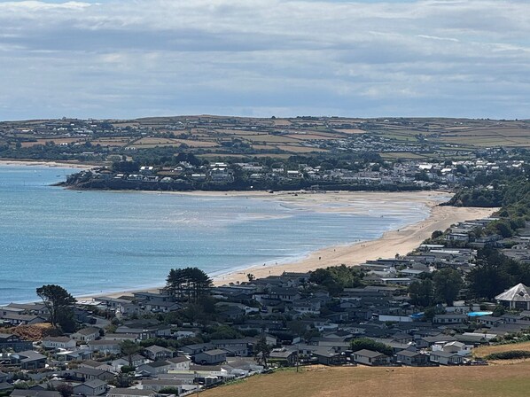 Un pueblo costero con playa, casas y un paisaje montañoso al fondo.