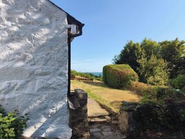 Un edificio blanco con un camino de piedra que lleva a un área de picnic y vistas al mar.
