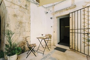 Un petit espace extérieur aménagé avec une table et des chaises, une plante en pot et un portail en métal.