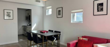 Un salon moderne avec un coin repas, un canapé rouge et des tableaux encadrés accrochés aux murs.