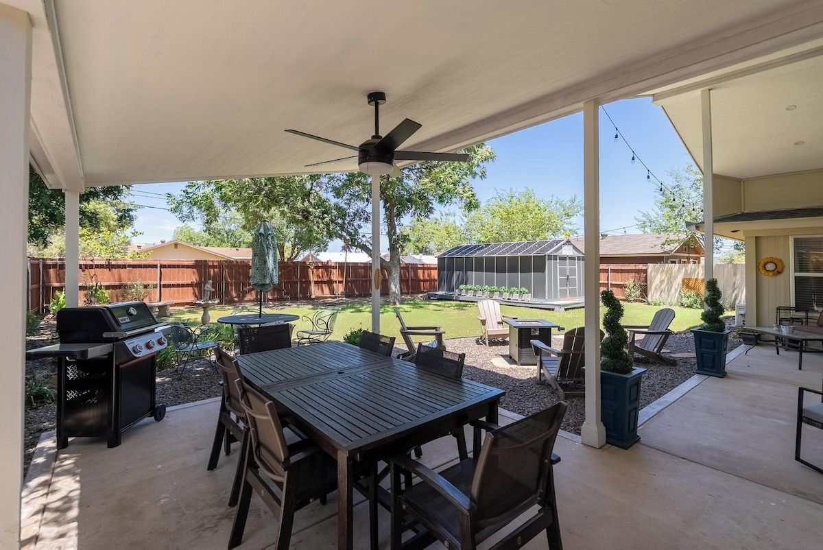 Un patio exterior con mesa y sillas, un ventilador de techo y una parrilla.