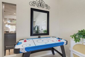 Een kamer met een tafelvoetbaltafel, een spiegel en een plant.