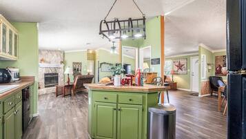A kitchen with green cabinets, a wooden countertop, and a hanging light fixture.