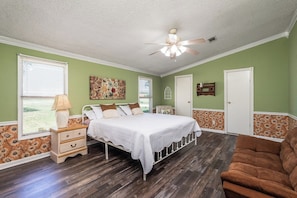 A bedroom with a bed, a nightstand, a chair, and a ceiling fan.
