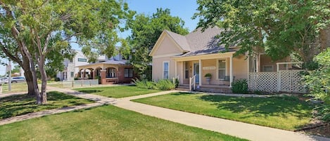 A residential house with a front porch, a pathway leading to the entrance, and a small front yard with grass and trees.