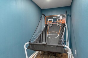 A room with a blue wall, a basketball hoop, and a netted area. - The Blue Bonnet – Charming 3-Bedroom Coastal (Abilene)