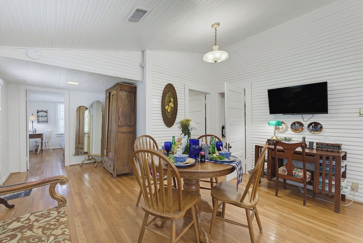 A dining area with a wooden table, chairs, and a television mounted on the wall.