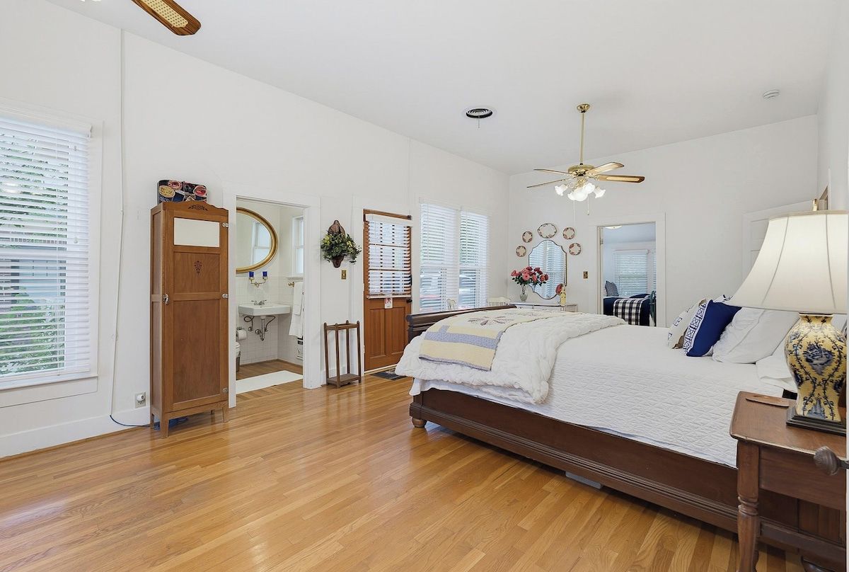 Un dormitorio con una cama de madera, un ventilador de techo y una mesita de noche con una lámpara.