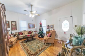 A cozy living room with a fireplace, a Christmas tree, and a ceiling fan.